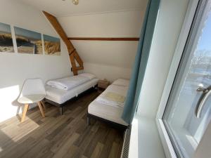 a small room with two beds and a window at Hotel Restaurant de Boekanier in Vrouwenpolder