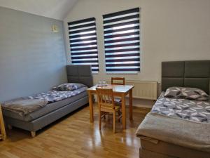 リブニクにあるVilla Basiaのベッド2台、テーブル、椅子が備わる客室です。