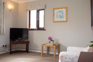 a living room with a tv and a couch and a table at Goitre Bach Llwyncelyn in Llanarth