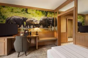 a bedroom with a desk and a painting of elephants at Amedia Hotel & Suites Leipzig, Trademark Collection by Wyndham in Leipzig