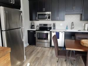 a kitchen with black cabinets and a stainless steel refrigerator at Spacious Condo Downtown Traverse City in Traverse City