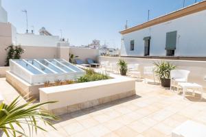 un patio en la azotea con mesas y sillas en un edificio en Villalobos Suites by Luxury Suites Cadíz en Cádiz