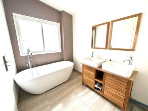 ein Badezimmer mit zwei Waschbecken, einer Badewanne und zwei Fenstern in der Unterkunft Tout confort 4 chambres - Jacuzzi - Barbecue - Jardin in Libourne