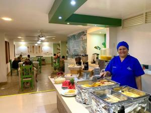 a woman standing in a kitchen preparing food at Hotel Valladolid in Santa Marta