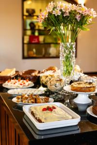 a table with plates of food and a vase of flowers at Hotel Petrópolis in Nova Petrópolis