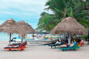 亭可馬里的住宿－Hema Holiday Villa，一群人坐在海滩上太阳伞下的椅子上