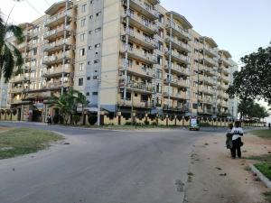 two people standing in front of a large apartment building at Blessie Ocean View Home in Dar es Salaam