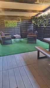 a patio with chairs and tables on a green floor at Loft indépendant Proche Paris in Villebon-sur-Yvette