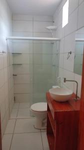 a bathroom with a toilet and a glass shower at Tambazulik pousada in Maragogi