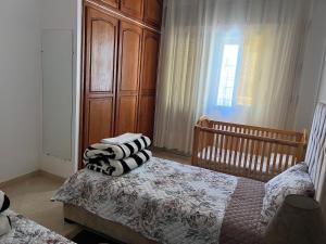 a bedroom with a bed with a wooden cabinet and a window at Cozy appartement Tanger in Tangier