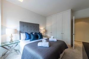 a bedroom with a large bed with blue pillows at Chelsea Pelham Apartments in London