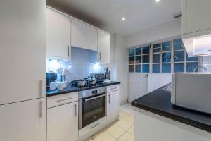 een keuken met witte kasten en een zwart aanrecht bij Chelsea Pelham Apartments in Londen