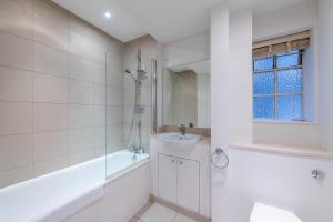 een witte badkamer met een bad en een wastafel bij Chelsea Pelham Apartments in Londen