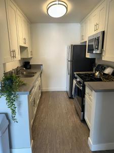 una cocina con armarios blancos y electrodomésticos de acero inoxidable en Hollywood two bedroom apartments close to Studios Universal, en Los Ángeles