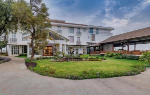 a large white building with a garden in front of it at Highland Club Kolhapur in Kolhapur