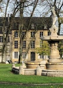 um grande edifício de pedra com uma fonte em frente em Le Mûrier de Bayeux em Bayeux