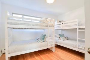 two white bunk beds in a white room with wood floors at Cheerful 3 Bedroom Beach Front Cottage with Fire Place in Milford