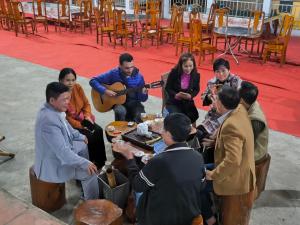 eine Gruppe von Menschen, die am Tisch sitzen und Musik spielen in der Unterkunft Son Thuy Homestay in Ha Giang
