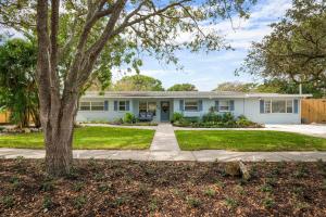 une maison blanche avec un arbre et un trottoir dans l'établissement Coastal Vibes! Tropical heated pool home short drive to the beach, à Bradenton