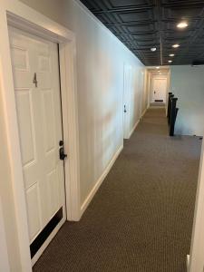 un couloir de bureau avec une porte blanche et un hallwayngthngthngthngthngthngthngthngth dans l'établissement Northport Inn Boutique Hotel Room 9, à Northport