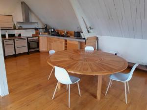 a kitchen with a wooden table and white chairs at la maison dans les bois in Soucelles +24 photos