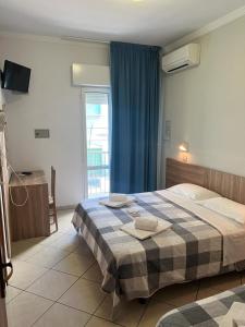 una camera da letto con un letto e due asciugamani di Hotel Blue Ribbon a Rimini