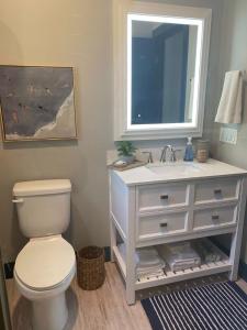 a bathroom with a toilet and a sink with a mirror at Modern Cottage in the Heart of Charlevoix in Charlevoix