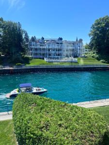 a boat in the water in front of a large house at Modern Cottage in the Heart of Charlevoix in Charlevoix