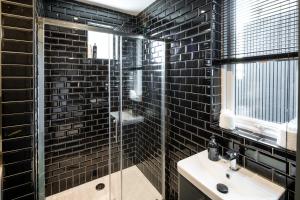 a black tiled bathroom with a sink and a shower at Beautiful 3BD Designer Apartment in London