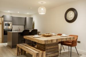 a kitchen and dining room with a wooden table and a clock at Exclusive Penthouse- 85 Inch Huge TV in Bradford