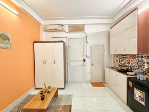 a kitchen with white cabinets and an orange wall at Sweet home * Center * Cozy in Hanoi