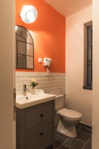 an orange bathroom with a toilet and a sink at VILLA TOURI - Touri Alpesi Birtok in Bozsok