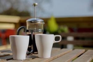 Duas chávenas brancas sentadas numa mesa com comodidades para preparar café em Chalet Fortysix em Deal