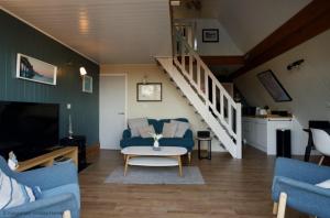 uma sala de estar com um sofá azul e uma escada em Chalet Fortysix em Deal