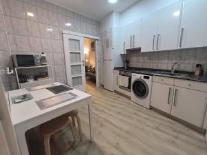 a kitchen with white cabinets and a washer and dryer at Apartamento Zabala conoce Bilbao desde dentro in Bilbao
