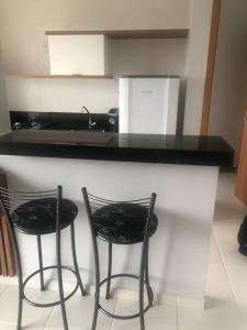 due sedie nere sedute al bancone della cucina di Flat Vereda, 524 -Rio quente. a Rio Quente