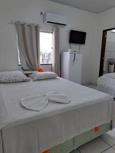 Una cama blanca con dos sombreros encima. en Hotel Monte Arau en Boa Vista
