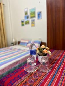 a table with a bottle and glasses and a bowl of flowers at Huong Thao Hostel & Tours in Dien Bien Phu