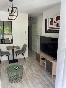 sala de estar con TV, mesa y sillas en Studio coin nuit terrasse parking Clim, en Niza