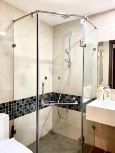 a glass shower in a bathroom with a sink at Golden Apartment in Ho Chi Minh City