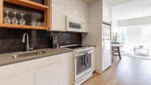 eine Küche mit weißen Schränken und Edelstahlgeräten in der Unterkunft Landing - Modern Apartment with Amazing Amenities (ID6942X44) in Portland