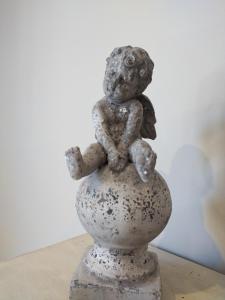 a small statue of a little angel sitting on a vase at Le mas de Roussillon chambre d'hôtes in Roussillon