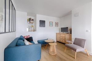 uma sala de estar com um sofá azul e uma cadeira em Résidor - Warm and bright 6P apartment! em Paris