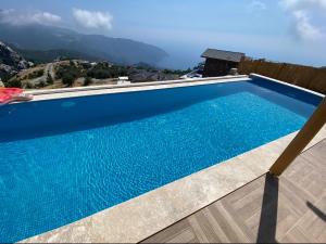 uma piscina azul com montanhas ao fundo em ALINCA İNFiNİTY VİLLA em Karaagac