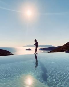 a person standing on top of a body of water at On The Rocks Villas Ios in Ios Chora