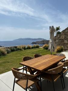 a wooden table and chairs with a view of the ocean at On The Rocks Villas Ios in Ios Chora