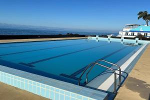 a large swimming pool with the ocean in the background at Saudades do Sol y Mar Apartment in Lagoa