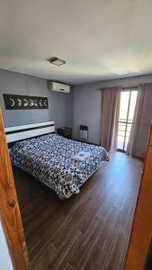 1 dormitorio con 1 cama y suelo de madera en Casa Ruta en General Villegas