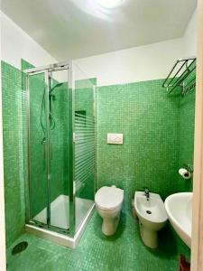 uma casa de banho com azulejos verdes, um WC e um chuveiro em Casa Nicanto - Near the Sea em Meta