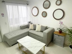 ein Wohnzimmer mit einem Sofa und Spiegeln an der Wand in der Unterkunft Suite Jacarandas 103 in Guadalajara